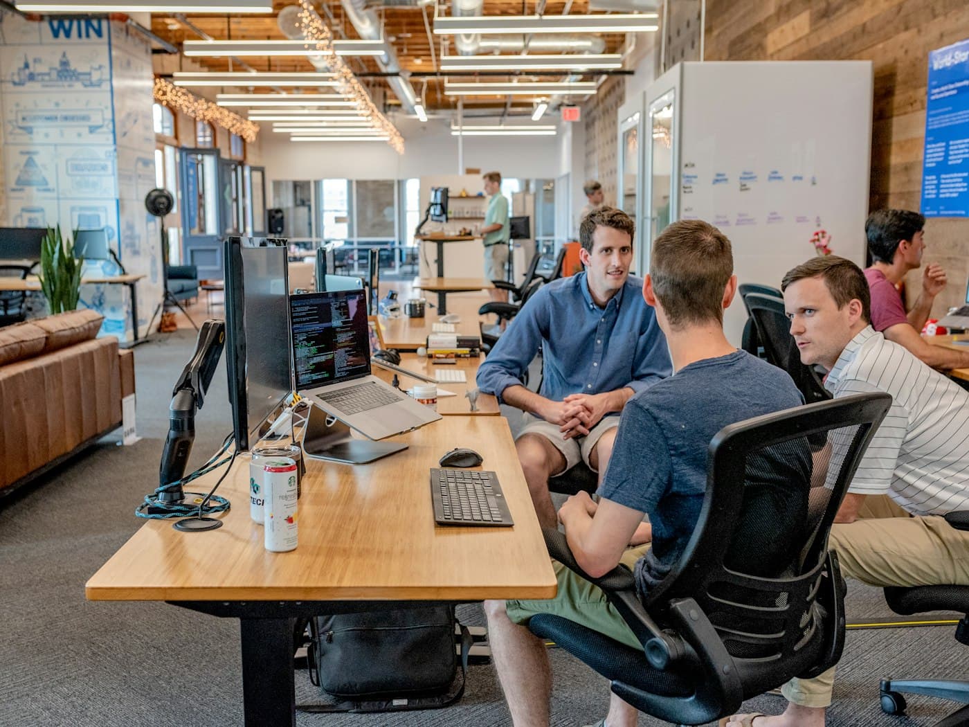 A small technology team talking through work at a shared desk